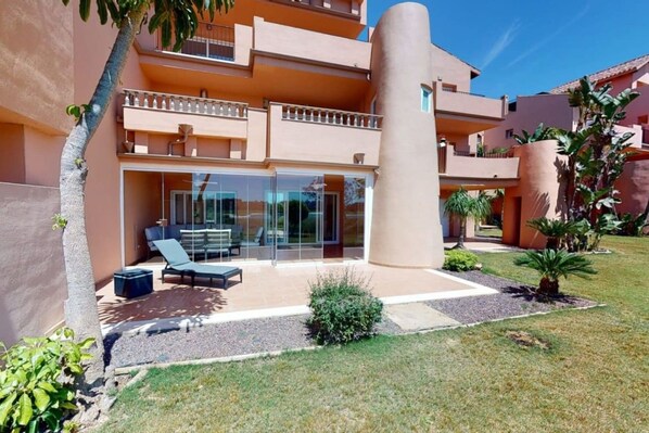 A modern building with a glass entrance, outdoor seating, and a well-maintained garden. - Spacious ground floor apartment - EO2402MM (Mar Menor Golf Resort)