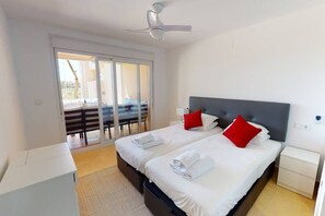 Une chambre d’hôtel comprenant un lit, une table de chevet, un bureau et une porte-fenêtre coulissante donnant sur un espace extérieur.