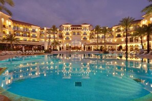Un hôtel doté d’une grande piscine, de nombreux balcons et de palmiers.