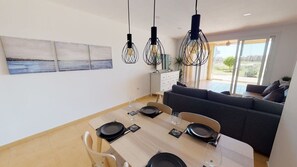 A dining area with a table set for four, a sofa, and pendant lights.