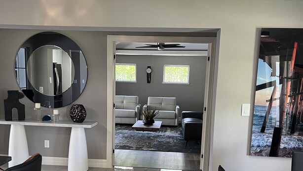 A modern living room with a large mirror, a round table, and a seating area with two sofas. -  Luxury Waterfront Retreat, 5thAve,  Private Pool, Dock & Sunset View Naples Bay (Naples)
