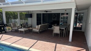 A covered patio area with a pool, outdoor furniture, and a ceiling fan. -  Luxury Waterfront Retreat, 5thAve,  Private Pool, Dock & Sunset View Naples Bay (Naples)