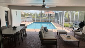 A covered outdoor area with a pool, seating, and a barbecue grill. -  Luxury Waterfront Retreat, 5thAve,  Private Pool, Dock & Sunset View Naples Bay (Naples)