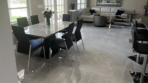 A modern living room with a dining area, featuring a marble floor, a sofa set, and a coffee table. -  Luxury Waterfront Retreat, 5thAve,  Private Pool, Dock & Sunset View Naples Bay (Naples)