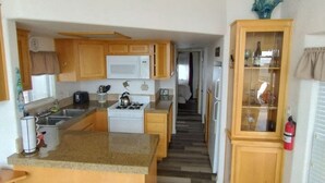 A kitchen with wooden cabinets, a white stove, and a built-in island with stools. - Ocean Front Cabin 16 with Private Jacuzzi & Incredible Views (Private Beach by White Rock Resort) (Smith River)