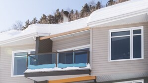 A two-story residential building with a balcony on the upper floor, a front door, and a staircase leading up to the entrance. - Le Bionick- Condo à louer Stoneham  (Stoneham-et-Tewkesbury)