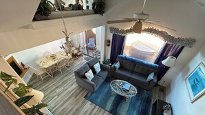 Een ruime woonkamer met een bank, salontafel en eethoek.