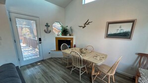 Een eetruimte met een houten tafel en stoelen, een open haard en een ingelijst schilderij aan de muur.