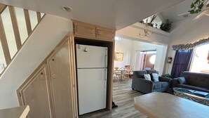 Een praktische keuken met een geïntegreerde koelkast, houten kastjes en een eethoek met tafel en stoelen.
