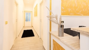 A hallway with a black rug, a reception desk with a vase, and a painting on the wall. - Trastevere Suites - Top Collection (Rome)