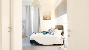 A modern bedroom with a large bed, a chandelier, and a marble floor. - Trastevere Suites - Top Collection (Rome)