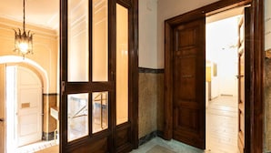 A hotel lobby with a grand wooden door, a chandelier, and a marble floor. - Trastevere Suites - Top Collection (Rome)