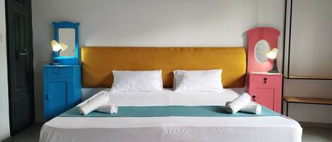 A neatly made bed with white linens, a teal bedspread, and two white pillows.