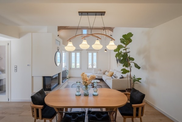 Una cocina moderna con zona de comedor, que incluye una mesa de madera, sillas negras e iluminación colgante.