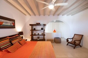 A bedroom with a bed, a wooden shelf, a chair, and a ceiling fan. - 360 Sunset Villa with Private Pool (Mikonos)