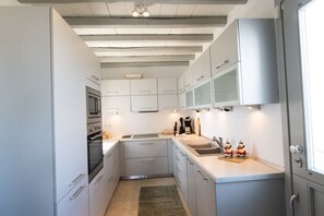 A modern kitchen with white cabinets, a built-in oven, a microwave, and a coffee maker. - 360 Sunset Villa with Private Pool (Mikonos)