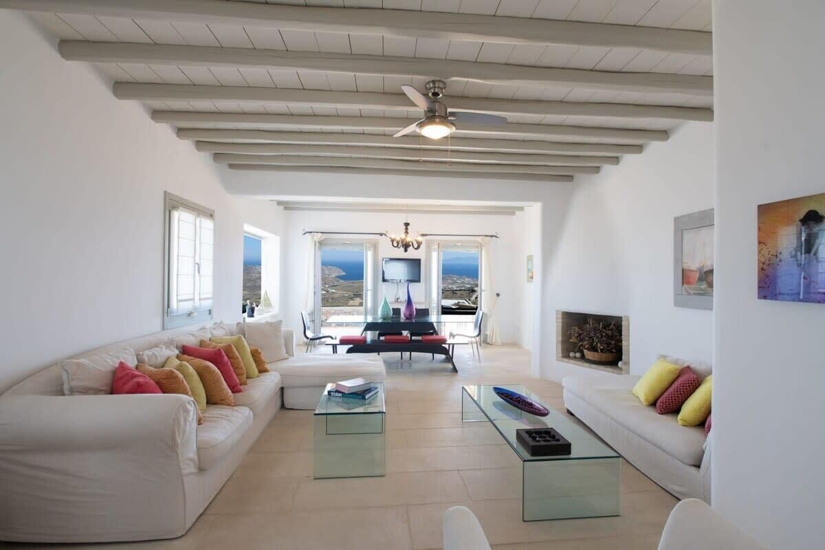 A spacious living room with a high ceiling, a dining area with a view, and a fireplace.