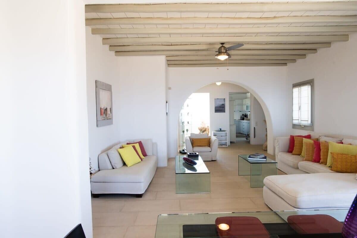 A modern living room with a sofa, coffee table, and a dining area with a table and chairs.