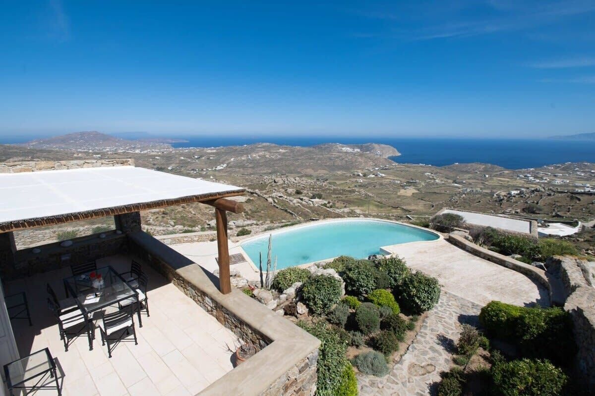 A rooftop patio with a pool, overlooking a coastal landscape.