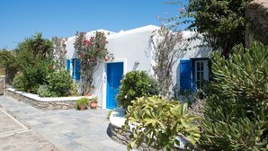 A white building with blue doors and windows, surrounded by greenery and potted plants. - Villa Victoria with Sea View and Two Private Pools (Mykonos)
