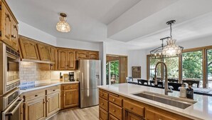 A modern kitchen with wooden cabinets, stainless steel appliances, and a large island with a sink.