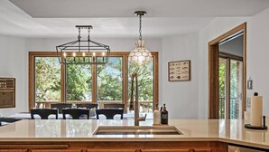 A kitchen with a large island, wooden cabinets, and a hanging light fixture.