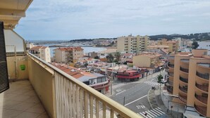 Ein Balkon mit Blick auf eine Küstenstadt, der eine Marina, Gebäude und eine Straße mit einem Stoppschild zeigt.