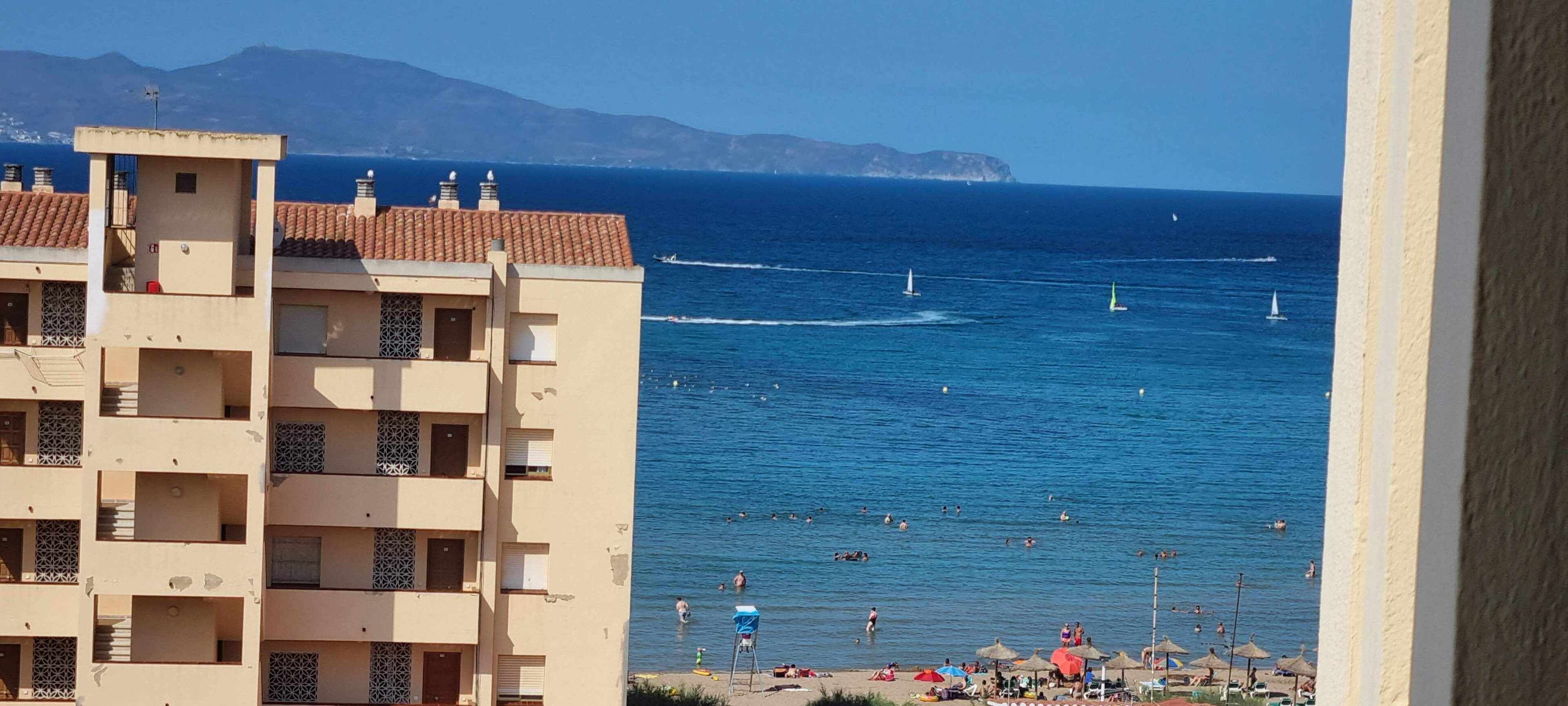 Vista costera con un edificio en primer plano y el mar al fondo.