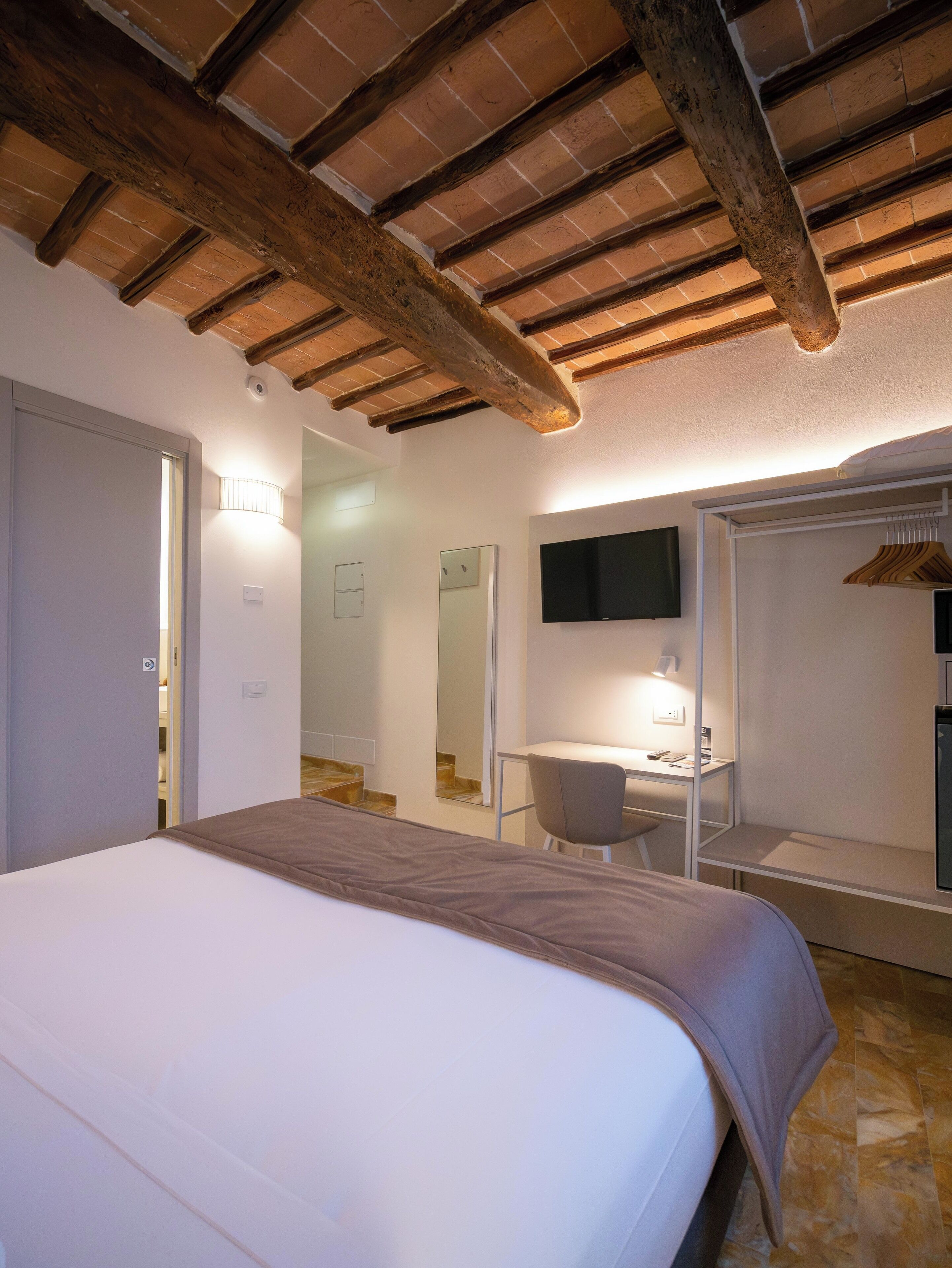 Un dormitorio con una cama, un escritorio, una silla, un televisor y un armario.