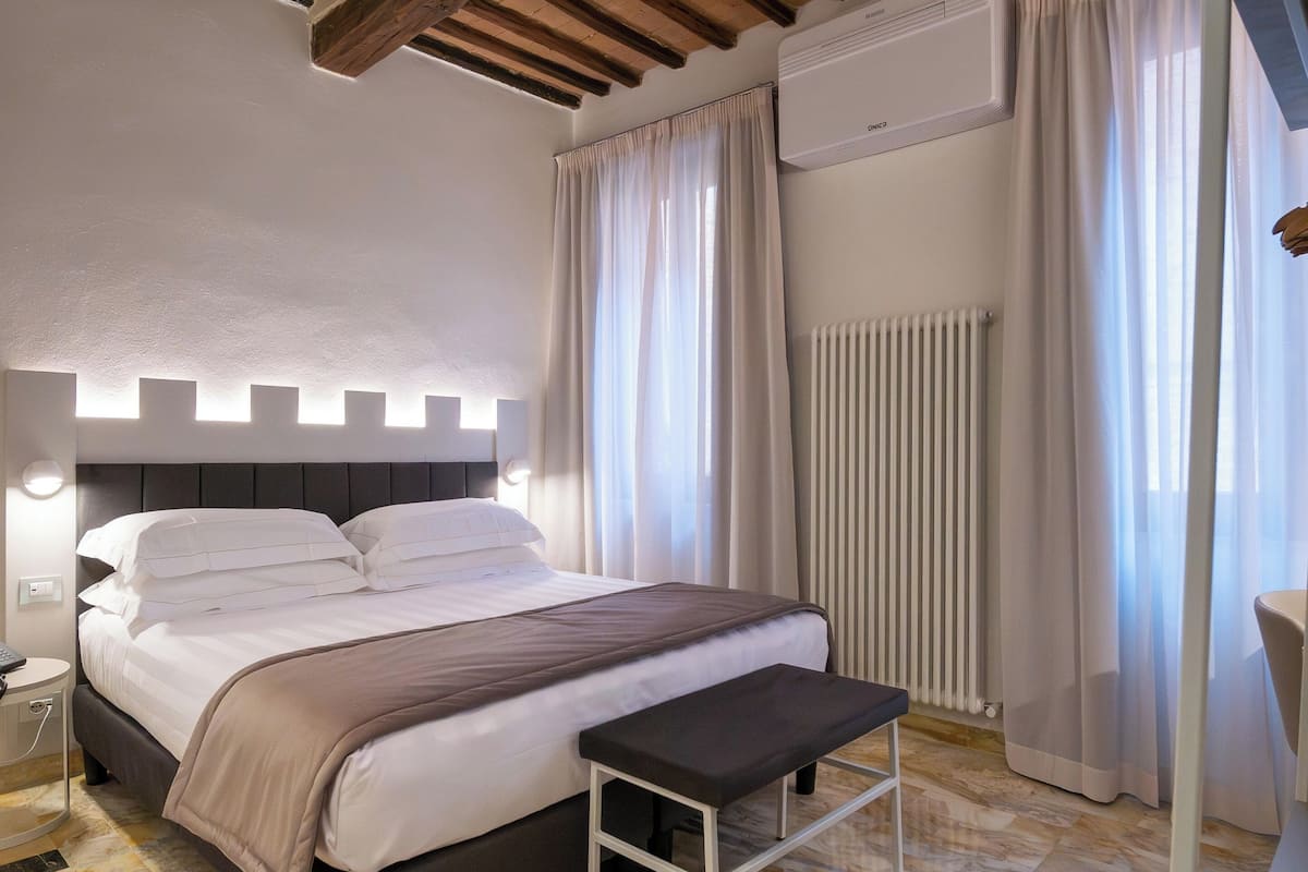 Un dormitorio moderno con cama, mesita de noche y un banco.