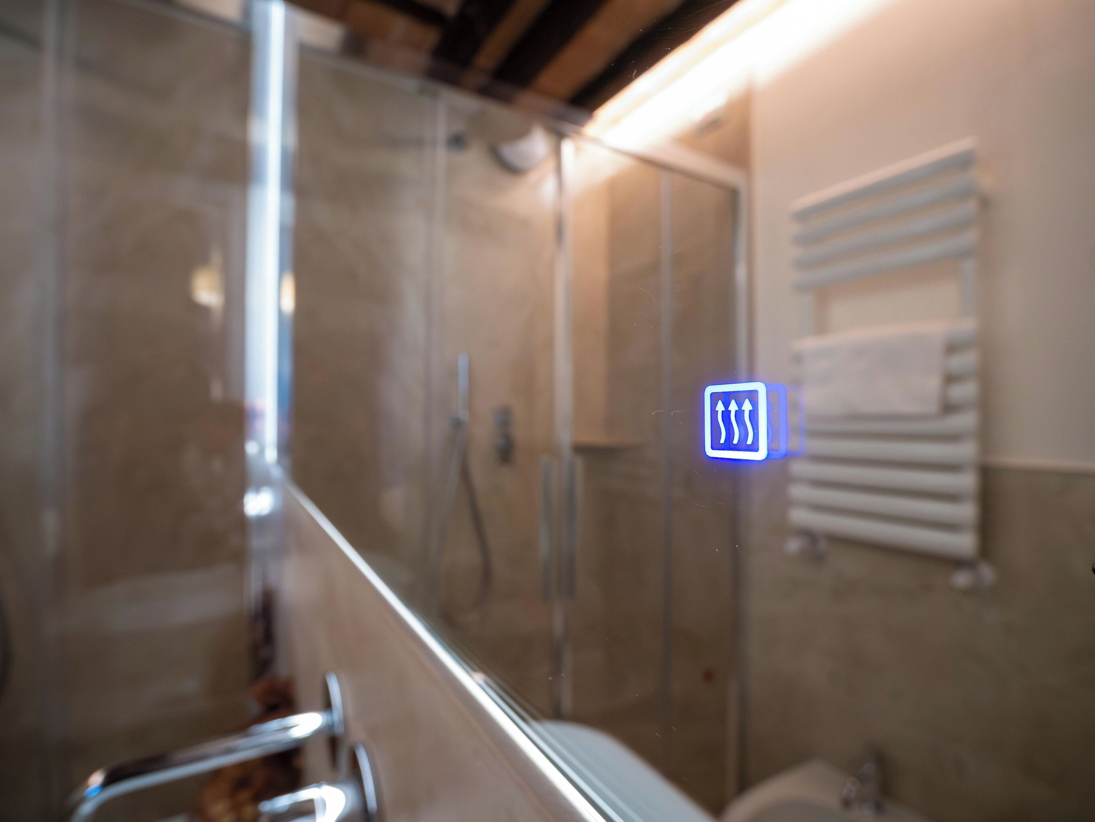 Un baño con cabina de ducha de vidrio, un perchero y un cartel con flechas.