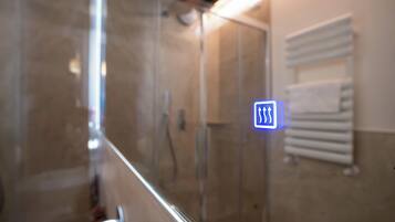 Un baño con cabina de ducha de vidrio, un perchero y un cartel con flechas.