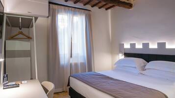 Un dormitorio con cama, escritorio y perchero.