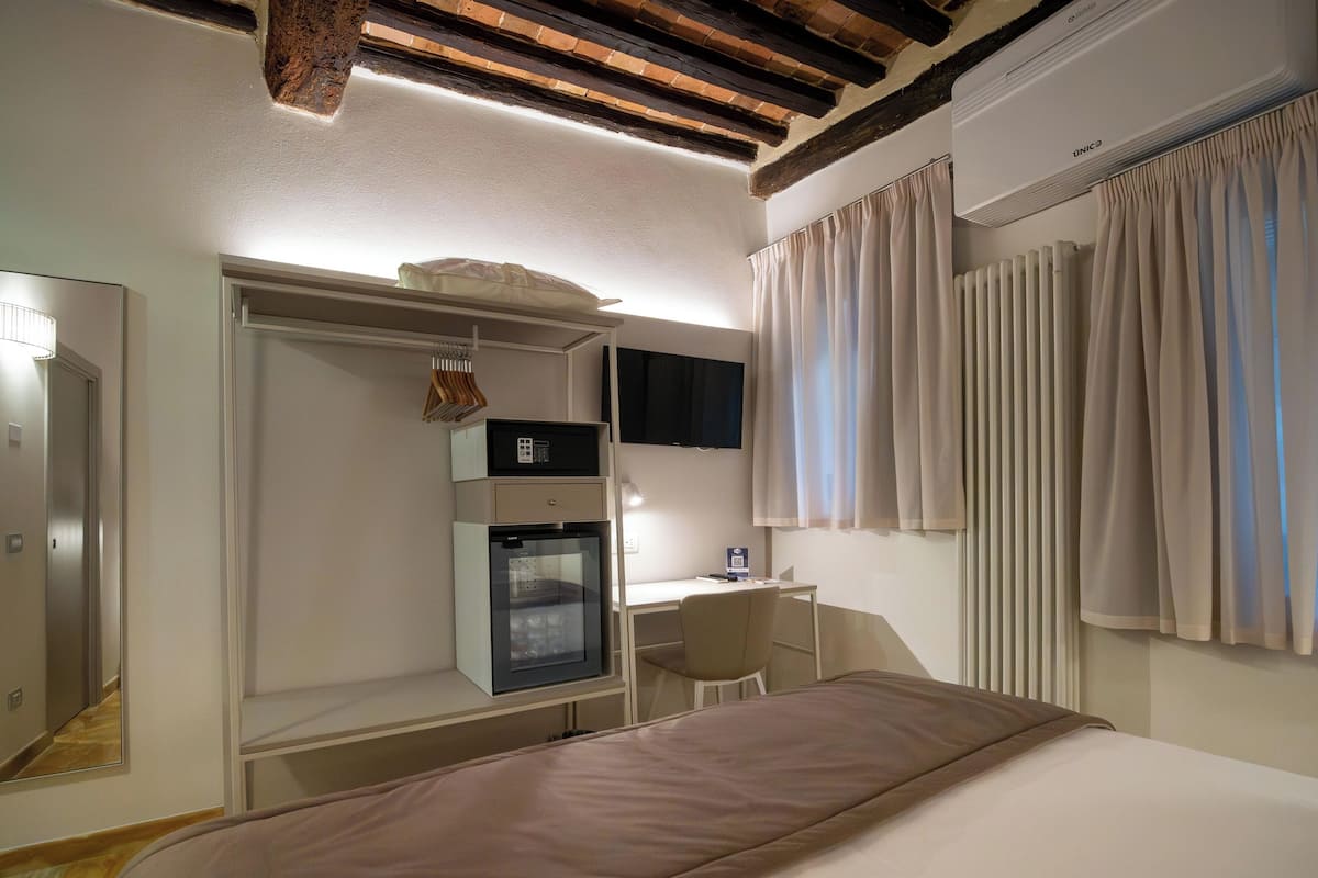 Habitación de hotel con cama, escritorio, minibar, televisor y armario.