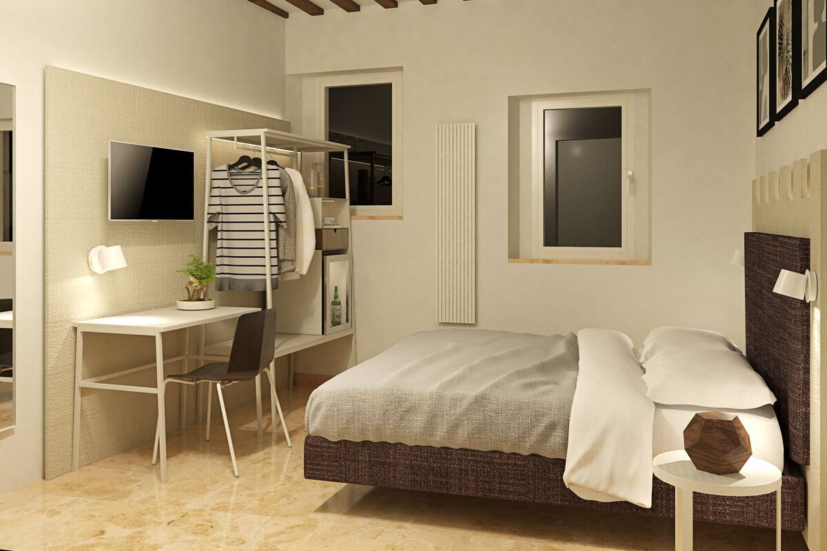 Un dormitorio con cama, escritorio, silla, televisor y armario.