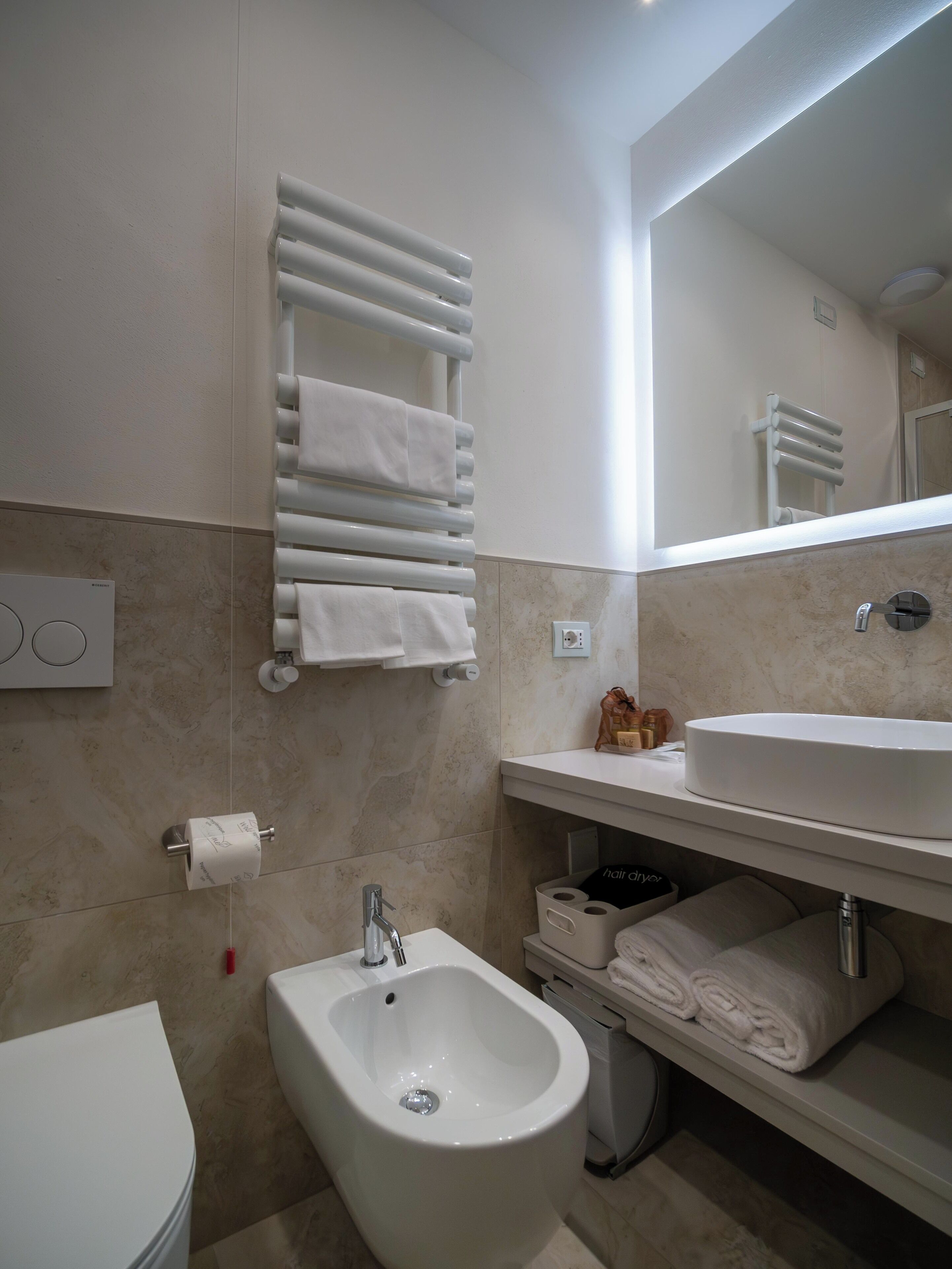 Un bagno moderno con bidet, lavandino e portasciuga.