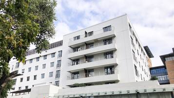 A multi-story building with balconies, large windows, and a gated entrance.