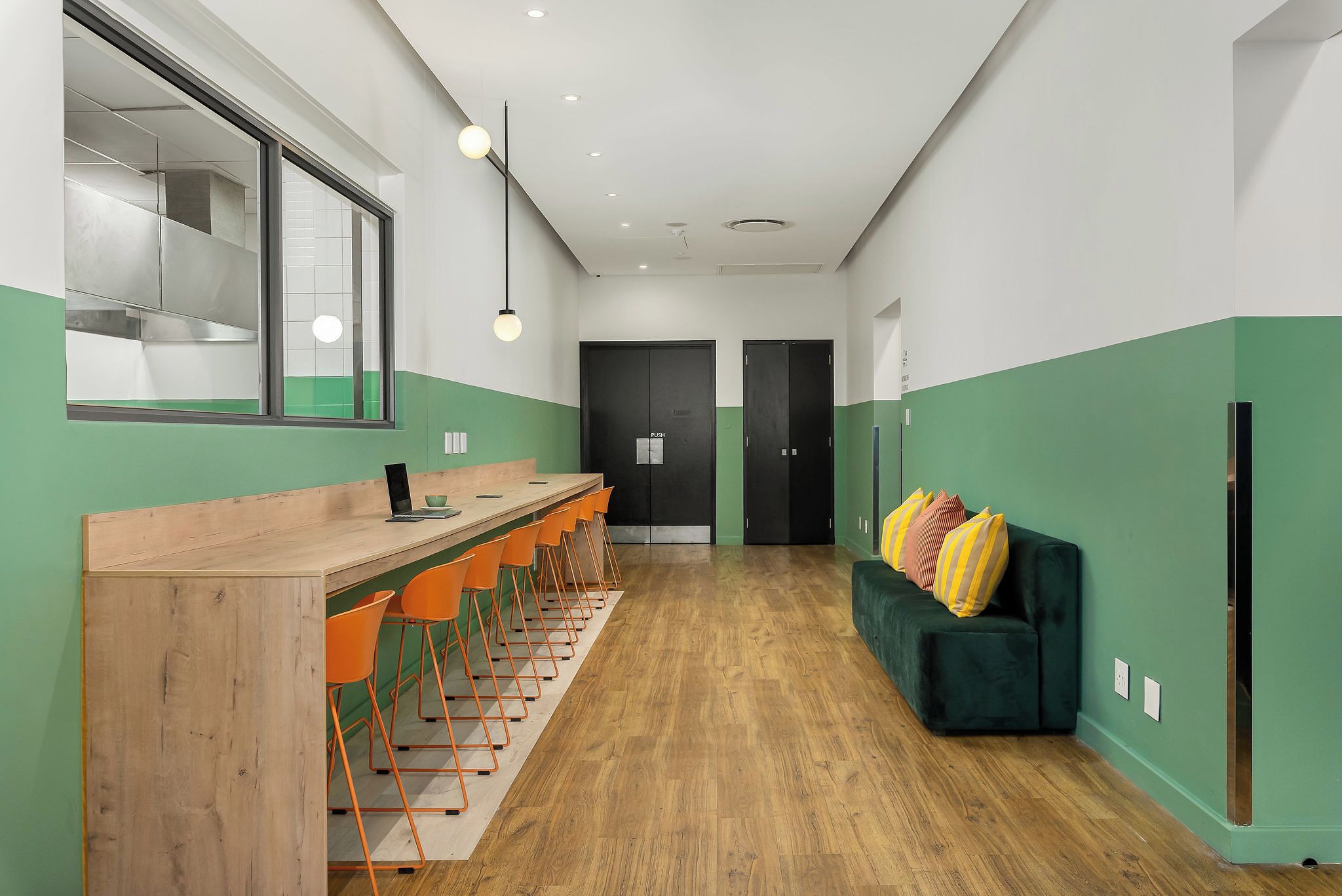 Una cocina moderna con barra, suelo de madera y paredes verdes.