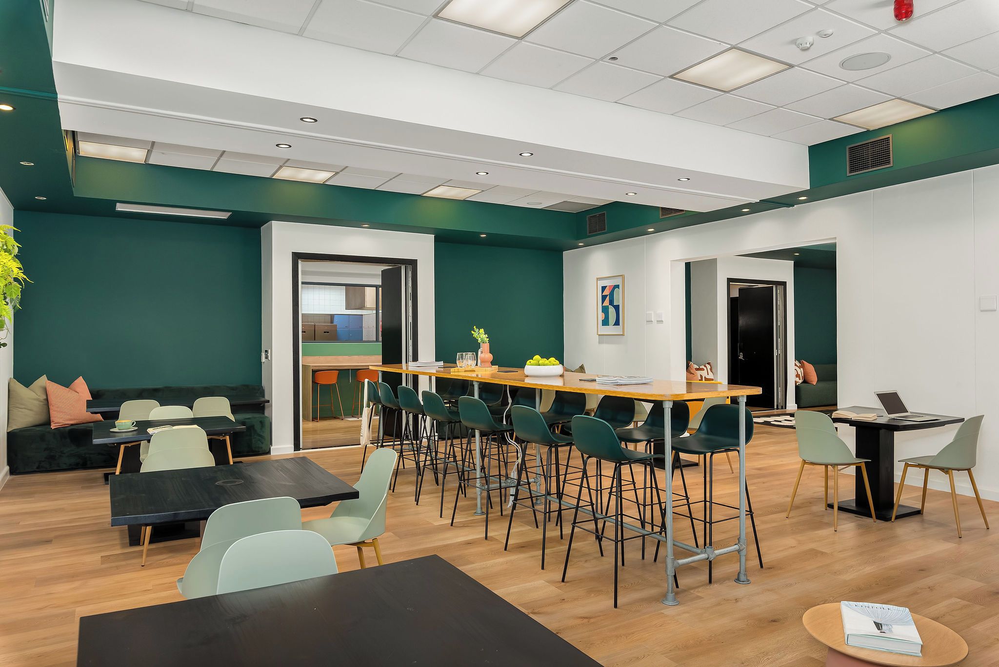 Ein moderner Konferenzraum mit einem langen Tisch, mehreren Stühlen und einer Küchenzeile im Hintergrund.