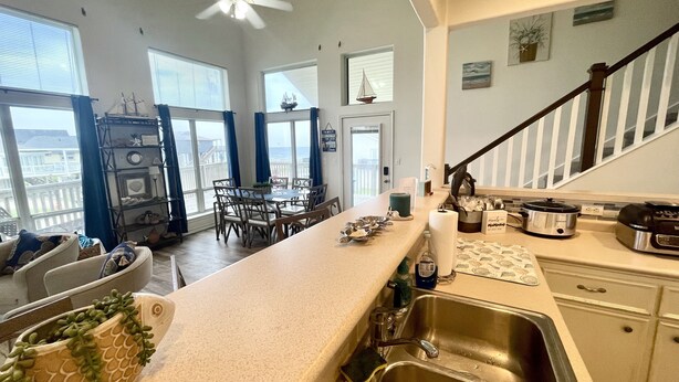 Une cuisine spacieuse dotée d’un grand îlot central, un coin repas offrant une vue agréable et un escalier menant à un balcon.