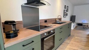 Een moderne keuken met een ingebouwde oven, een kookplaat en een afzuigkap. Er is een spoelbak en een koffieapparaat op het aanrecht.