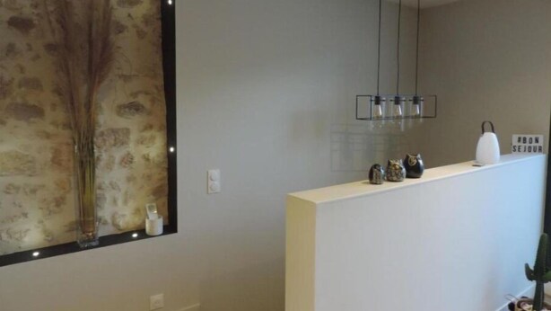 Een moderne badkamer met een grote spiegel, een hangende lamp en een decoratief object aan de wand.