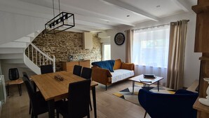 Een moderne woonkamer met een trap, een eethoek en een bank.