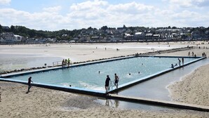 Een strand met een zwembad en mensen die van het water genieten.