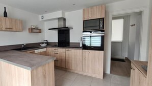 Een moderne keuken met houten kastjes, een ingebouwde magnetron en een roestvrijstalen afzuigkap.