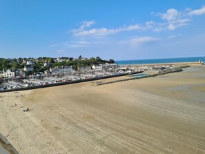 Uma vila costeira com um porto de recreio, praia de areia e edifícios residenciais.