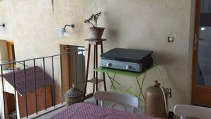 Ein kleiner, rustikaler Raum mit einem Holztisch, einer Topfpflanze, einem Transportheizgerät und einem Tisch mit einem Radio.