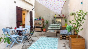 A cozy outdoor seating area with a table and chairs, a sofa, and a patterned rug. - L'Observance - Au cœur du centre historique (Arles)