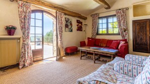 A cozy room with a red sofa, a wooden table, and a view through a glass door.