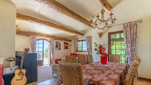 A rustic dining area with a patterned tablecloth, wicker chairs, and a guitar.